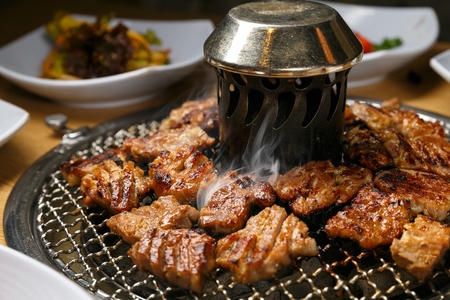 Marinated pork spareribs being grilled on charcoal grillの写真素材