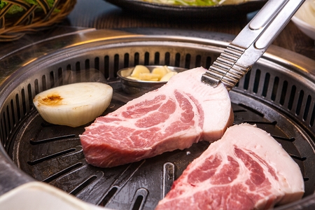 Pincers turning pork neck on black grillの写真素材