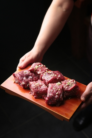 Chef holding a wooden cutting board containing rolled marinated pork spareribsの写真素材