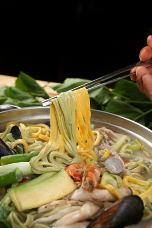 Chopsticks picking up mulberry leaves seafood noodles, noodles with seafood broth with mulberry leavesの写真素材