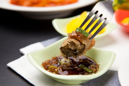 Fork dipping deep-fried glass noodles in seaweed, in soy sauceの写真素材