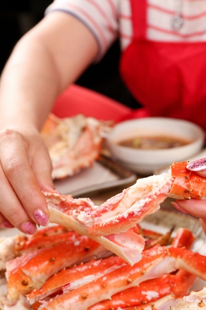 Chef defleshing legs of steamed king crab, on white plateの写真素材