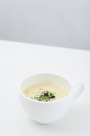 Potato cream soup in a white mug, on a white table