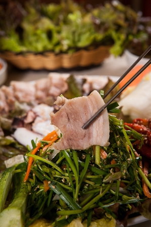 Chopsticks picking up boiled pork and chivesの写真素材