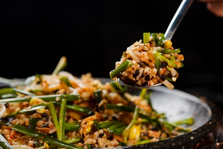 Spoon scooping up stir-fried rice with bean sprouts, chives, on black grillの写真素材