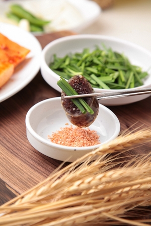 Chopsticks dipping korean sausages with sweet rice with chives in saltの写真素材