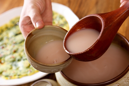 Ladle scooping up rice win from a pot, into a cup for rice wineの写真素材
