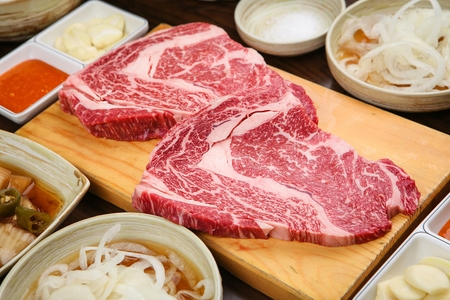 Beef sirloin and side dishes on wooden cutting boardの写真素材