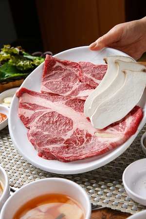 Beef sirloin, king oyster mushrooms and side dishes on white plateの写真素材