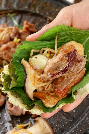 Lettuce, perilla leaf, king oyster mushroom, garlic, bean sprouts and duck meat wrapped in cabbage