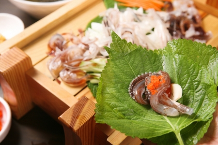 Raw squid wrapped in perilla leaf with garlic, sauce and flying fish roeの写真素材