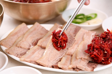 Chopsticks picking up pork belly and seasoned dried slices of daikon, on round plateの写真素材
