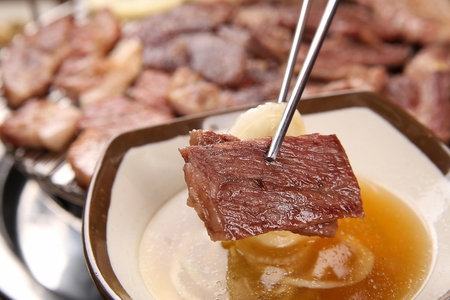 Chopsticks picking up grilled beef sirloin and seasoned onionsの写真素材