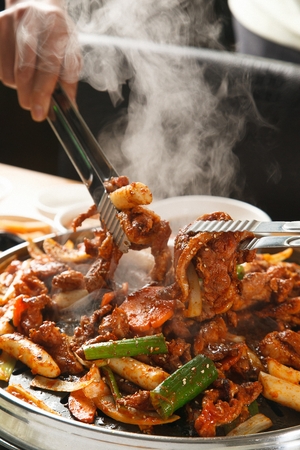 Grilled pork, vegetables and spicy sauce stir-fried on black grillの写真素材