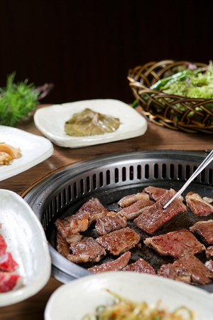 Chopsticks picking up beef sirloin being grilled on charcoal grillの写真素材