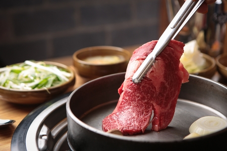 Pincers putting beef sirloin on black grillの写真素材