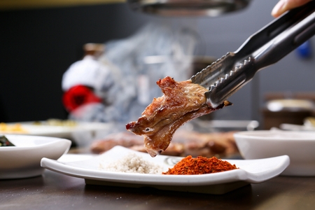 Pincers dipping grilled lamb ribs in sauceの写真素材