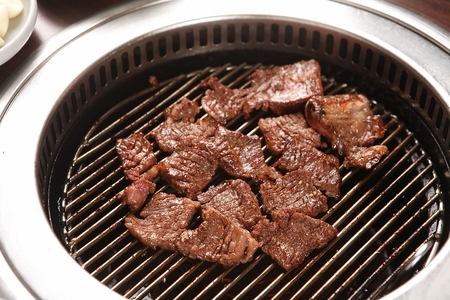 Marinated pork ribs being grilled on charcoal grillの写真素材