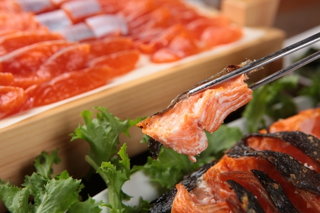 Chopsticks picking up grilled salmon on white round plateの写真素材