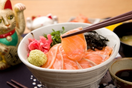 Chopsticks picking up salmon from salmon rice bowl, on round bowlの写真素材
