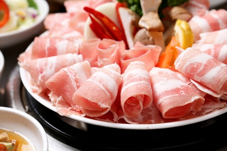 Thin pork belly, onions, king oyster mushrooms, carrots, lemon, chili on round plateの写真素材