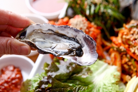 Hand picking up raw oysters on rectangular plateの写真素材
