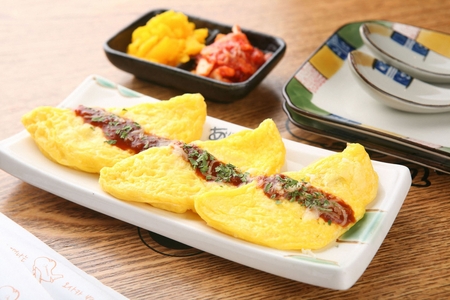 Omelette with sprinkled sauce and parsley powder on rectangular plateの写真素材