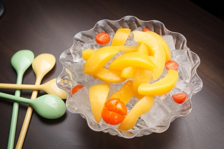 Ice, peaches and cherry tomatoes in transparent bowlの写真素材