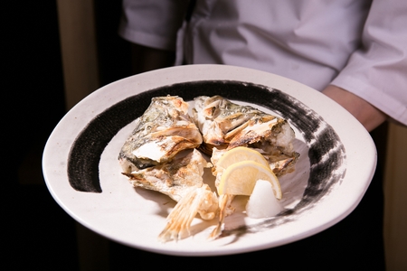 Chef holding a long white plate containing grilled breamsの写真素材