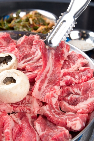 Pincers picking up beef rib meat on round plateの写真素材