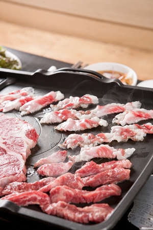 Beef sirloin, beef brisket, beef thin skirt being grilled on black grillの写真素材