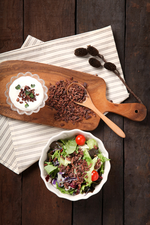 Dried cacao nips on wooden cutting board, and a salad with cacao nipsの写真素材