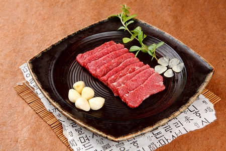 Beef sirloin and whole garlic on rectangular plateの写真素材