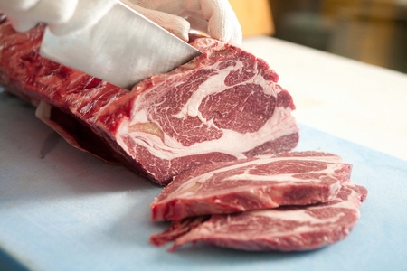 Knife cutting beef sirloin on cutting boardの写真素材