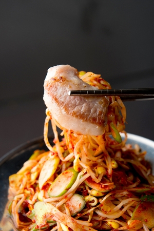 Chopsticks placing grilled pork neck on greensの写真素材