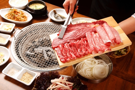 Pincers picking up Beef sirloin, beef brisket, beef thin skirt on wooden cutting boardの写真素材