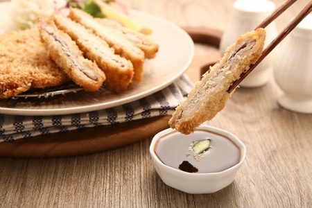 Fried pork cutlet in bowl, and chopsticks dipping fried pork cutlet in sauceの写真素材