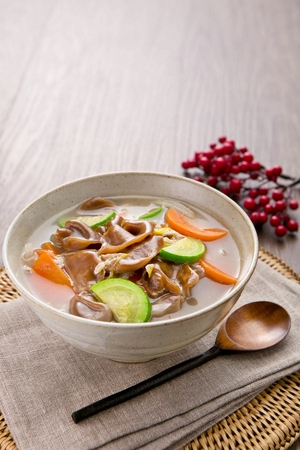 Hand-pulled dough soup made of acorns, including green pumpkin and carrots in china bowlの写真素材