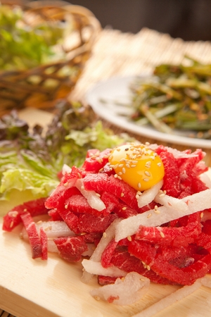Beef tartare with sliced pear and egg yolk, on wooden cutting boardの写真素材