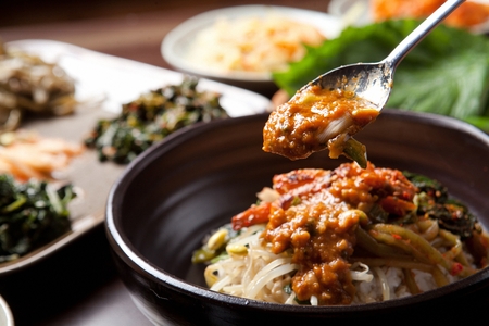 Sauce being placed on rice with various vegetablesの写真素材