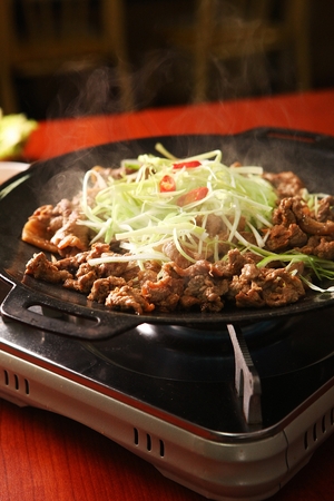 Marinated bulgogi with seasoned green onions, on iron plateの写真素材