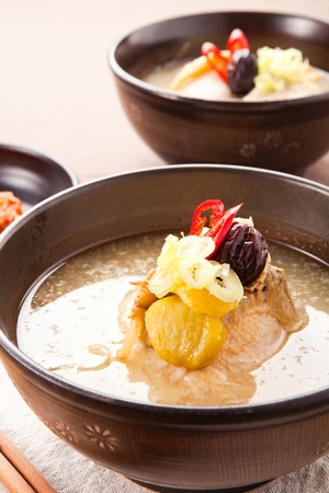 Chicken soup with walsh onion and chili garnish in china bowl, served with kimchiの写真素材