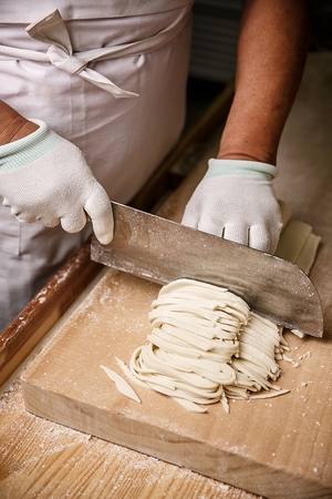 Chef making chopped noodles on cutting boardの写真素材