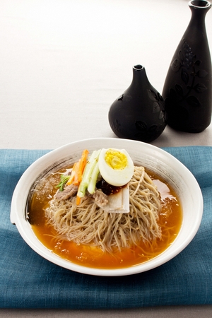 Cold buckwheat noodles soup with cucumber and eggs garnish, in bowlの写真素材