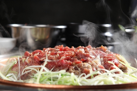 Marinated bulgogi with seasoned green onions, on iron plateの写真素材