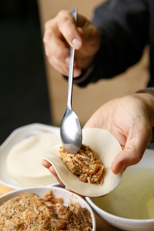 Spoon putting tofu, meat and vegetables in dumpling skinの写真素材