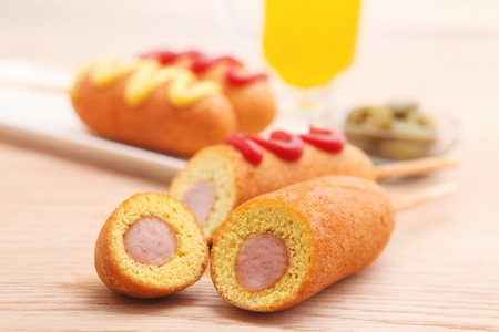 Hotdog with sprinkled ketchup and mustard, on white rectangular plateの写真素材