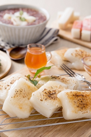 Baked rice cakes on cutting board and honey in bowl, with forkの写真素材