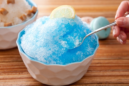 Blue lemon shaved ice with lemon slices, in white bowlの写真素材