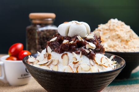 Adzuki beans shaved ice with glutinous rice cakes and almonds in black bowl